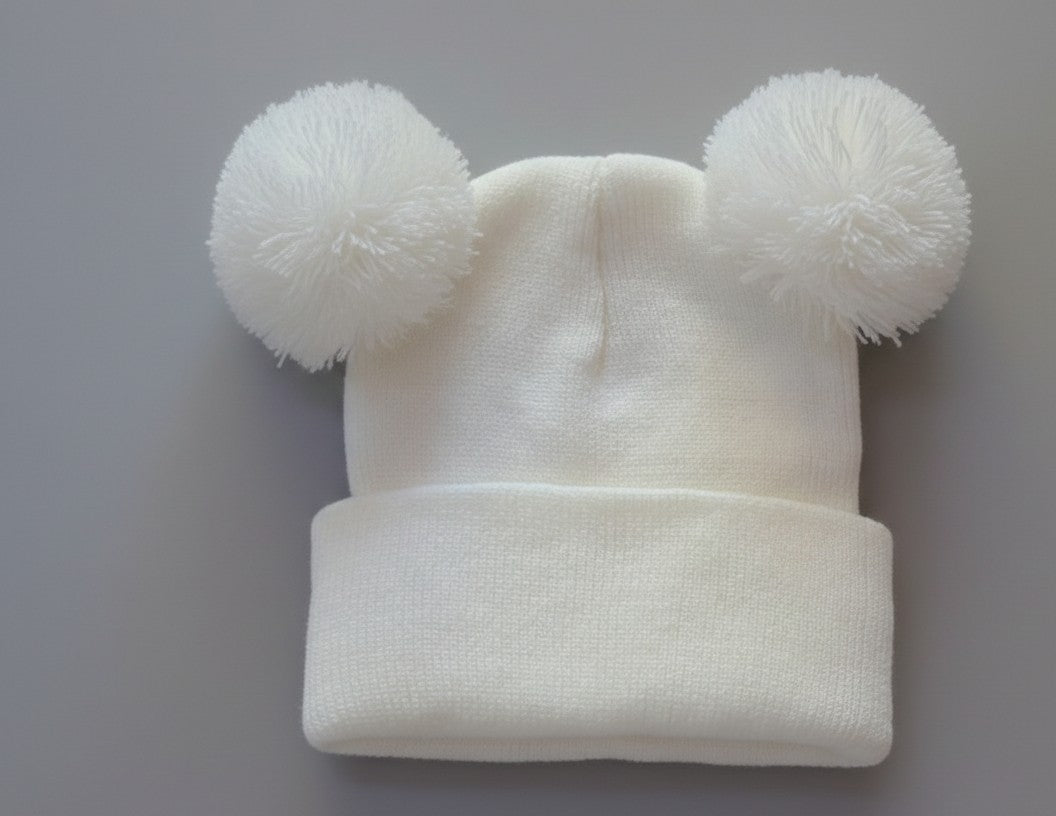 White personalised double pom pom baby beanie on grey background