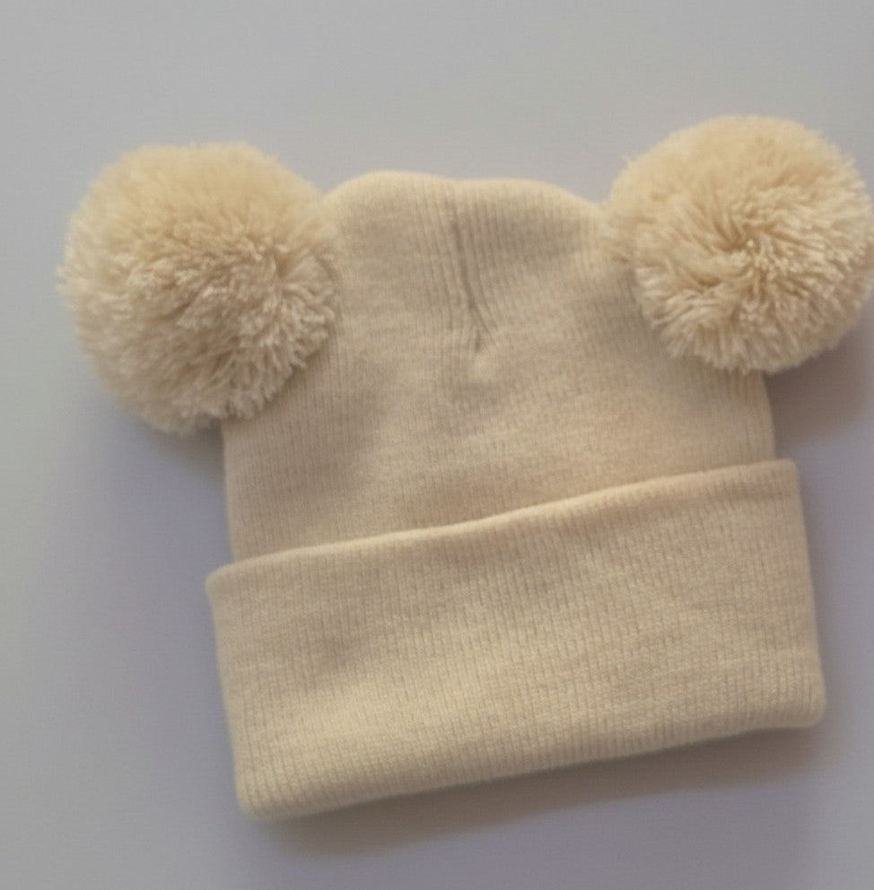 Cream personalised double pom pom baby beanie on grey background